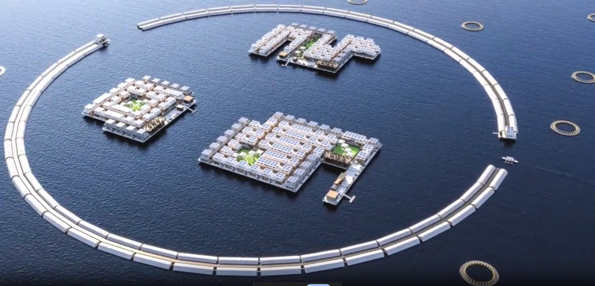 Render of a floating city: three districts of white low-rise blocks with planted courtyards and solar roofs, moored inside a large circular breakwater on deep blue water, with hexagonal fish pens ringing the outside